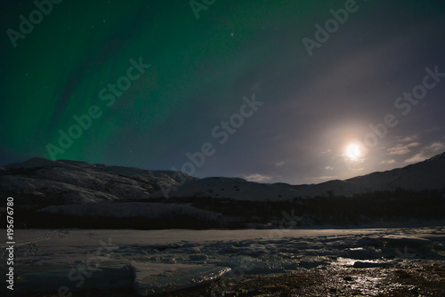 Night winter landscape with Moon and aurora borealis on the sky. Barents sea coastline, Kola peninsula, Russia. © SergeG