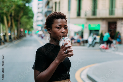 Woman, drinking beverage while crossing the street photo