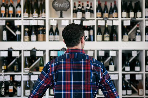 Wine: Man Overwhelmed In Front Of Wall Of Wine Choices
