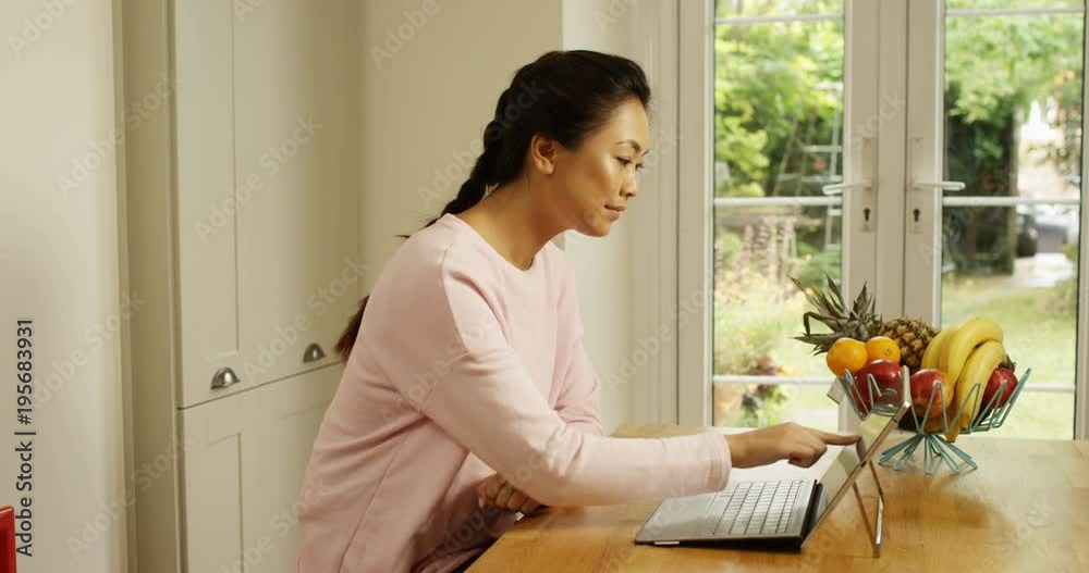 4K Smiling Asian woman at home using the internet on digital tablet with keyboard. Slow motion. 4K Smiling Asian woman at home using the internet on digital tablet with keyboard. Slow motion.