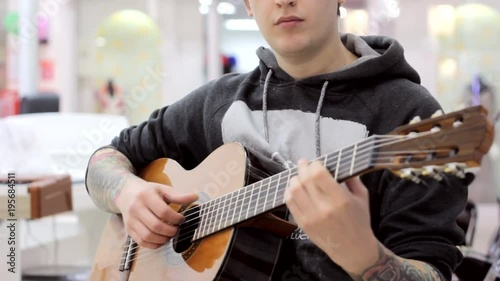 The guy plays a classical guitar in a music store, a musical mood, classical music.