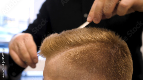 Close up of men's hair cutting scissors in a beauty salon. Master cuts hair and beard of men in the barbershop, hairdresser makes hairstyle for a young man. Close up of Man at the Hair salon