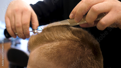 Close up of men's hair cutting scissors in a beauty salon. Master cuts hair and beard of men in the barbershop, hairdresser makes hairstyle for a young man. Close up of Man at the Hair salon