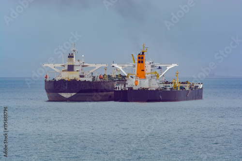 Loading anchored oil supertanker via a ship-to-ship oil transfer
