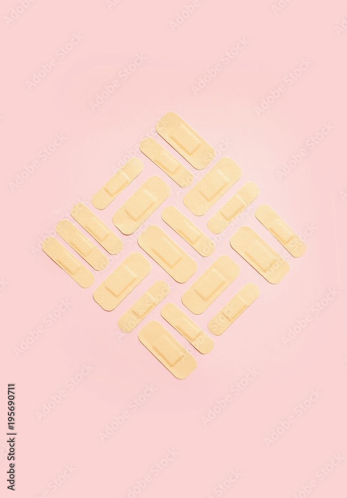 Square of adhesive bandages on pink background Square of adhesive bandages on pink background