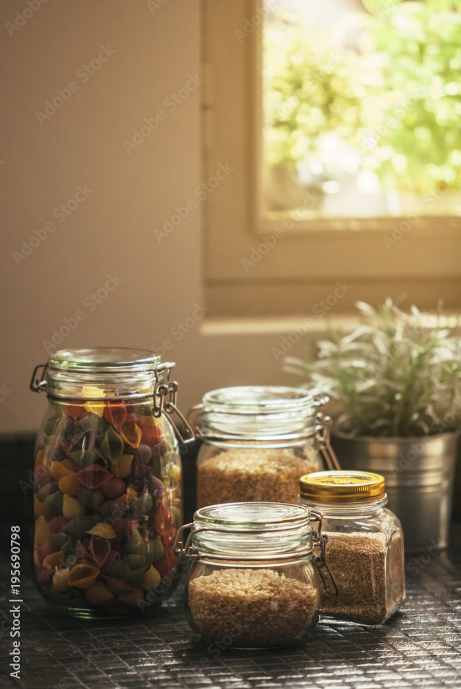 Glass Jars with pasta and seeds in a rustic kitchen Glass Jars with pasta and seeds in a rustic kitchen