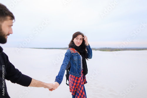 girlfriend and boyfriend walk at seaside, couple look for place for snack and rest. Young people with backpacks holding hands look around. Concept of beautiful landscapes, accessories, comforta photo