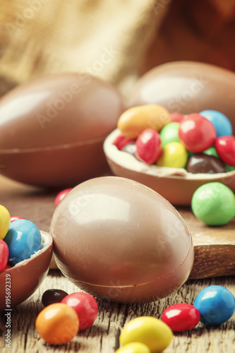 Easter composition with chocolate eggs and colorful candy, vintage wooden background, selective focus