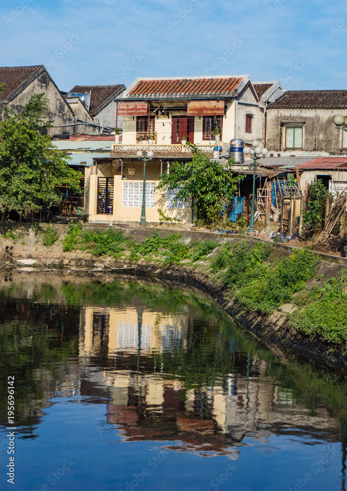 reflections of a neighborhood in old Hoi An on a canal