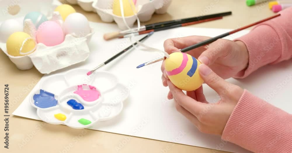 Coloring eggs for Easter with hands and a brush with watercolor paints