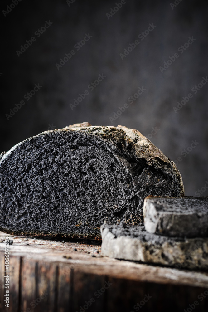 Fototapeta premium Sliced bread of black color on a wooden table