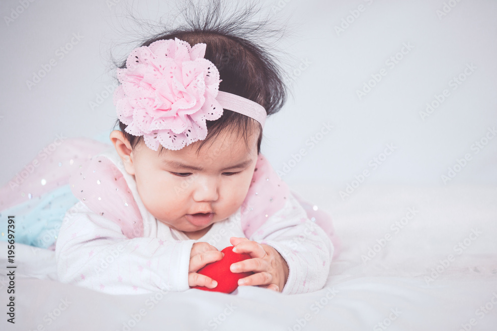 Cute asian baby girl lying on her stomach and play with her toy on the bed Cute asian baby girl lying on her stomach and play with her toy on the bed