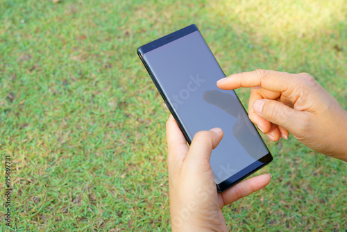 Female hand holding the smartphone Black and Green nature