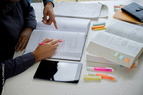 Education concept. Students studying and brainstorming campus concept. Close up of students discussing their subject on books textbooks and writing to notebook. Selective focus.