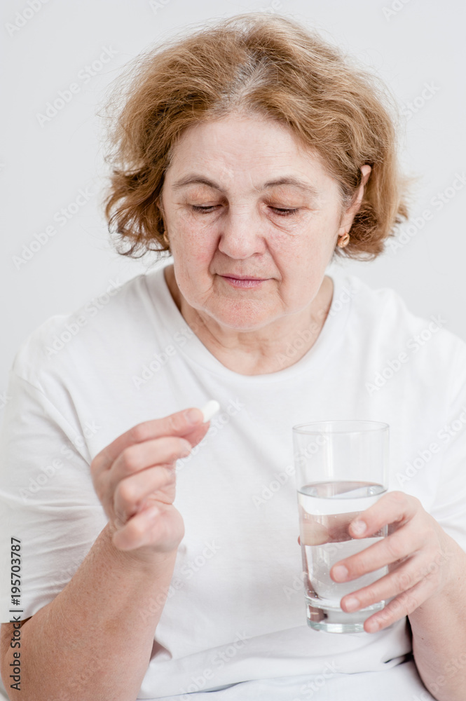 Senior woman holding pills and glass of water Senior woman holding pills and glass of water
