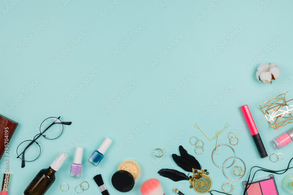 Beautiful fashion flatlay with various fashion accessories: glasses, cosmetics, jewelry, rings, etc. Copyspace, mint background, top view