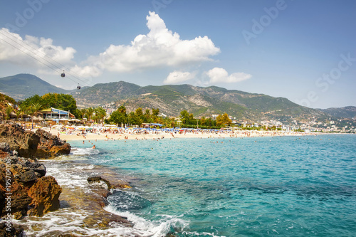 Tropical beach of Costa Brava on sunny summer day. Paradise lagoon on seaside resort of Spain. Tourists are bathing in the sea and sunbathing on beach. Sea landscape of nature of Mediterranean