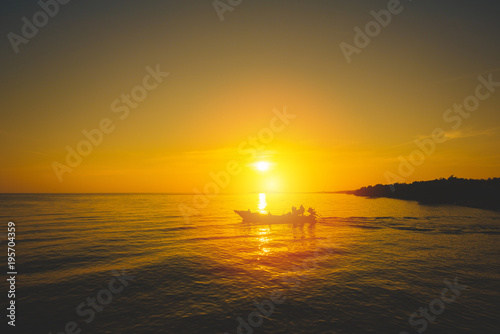 Silhouette of fishing boat and fisherman on sunset.