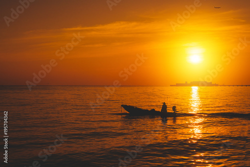 Silhouette of fishing boat and fisherman on sunset. © vacancylizm