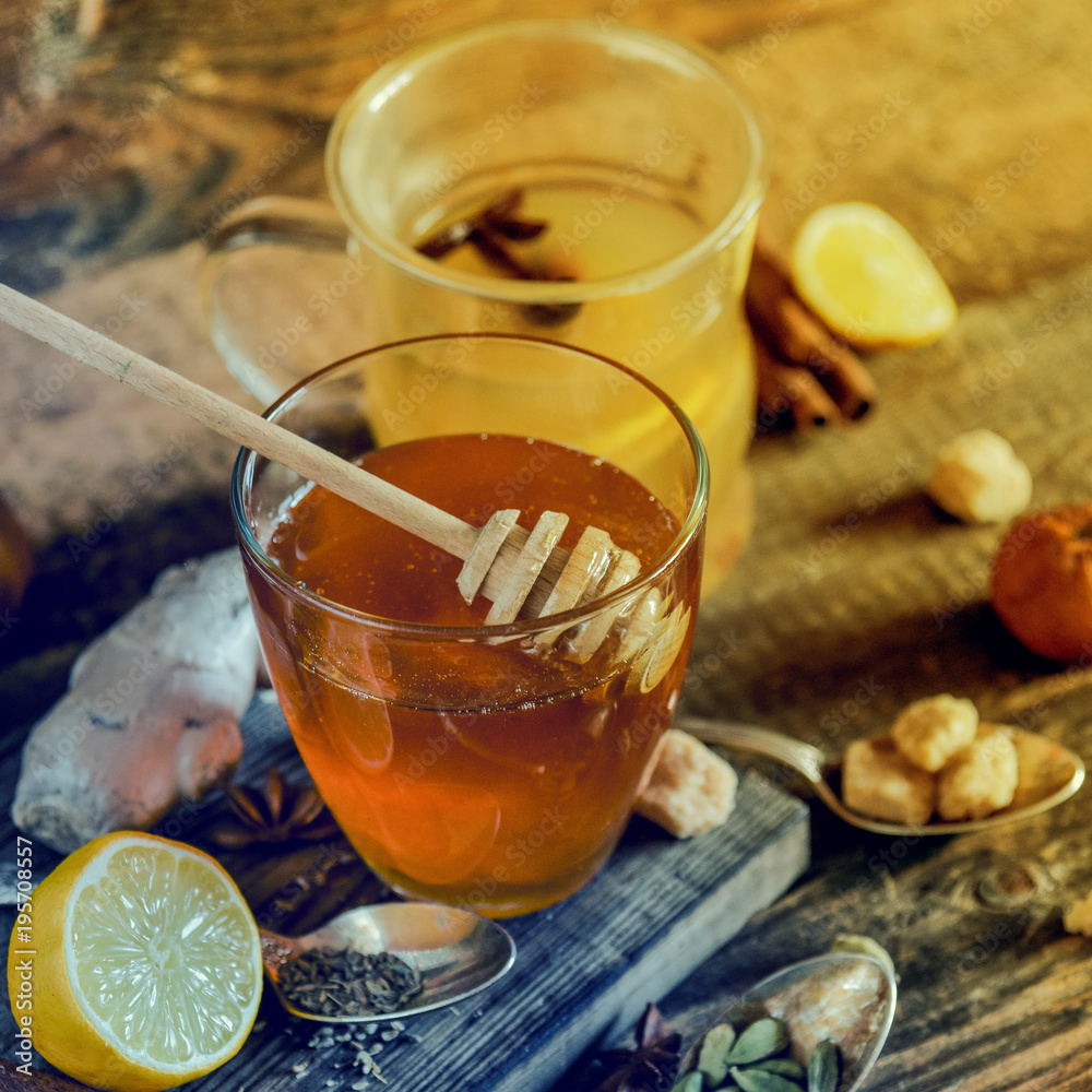 Vitamin healing tea with lemon and honey, ginger and spices on wooden background in rustic style. The concept of spring beriberi and colds. Square image.