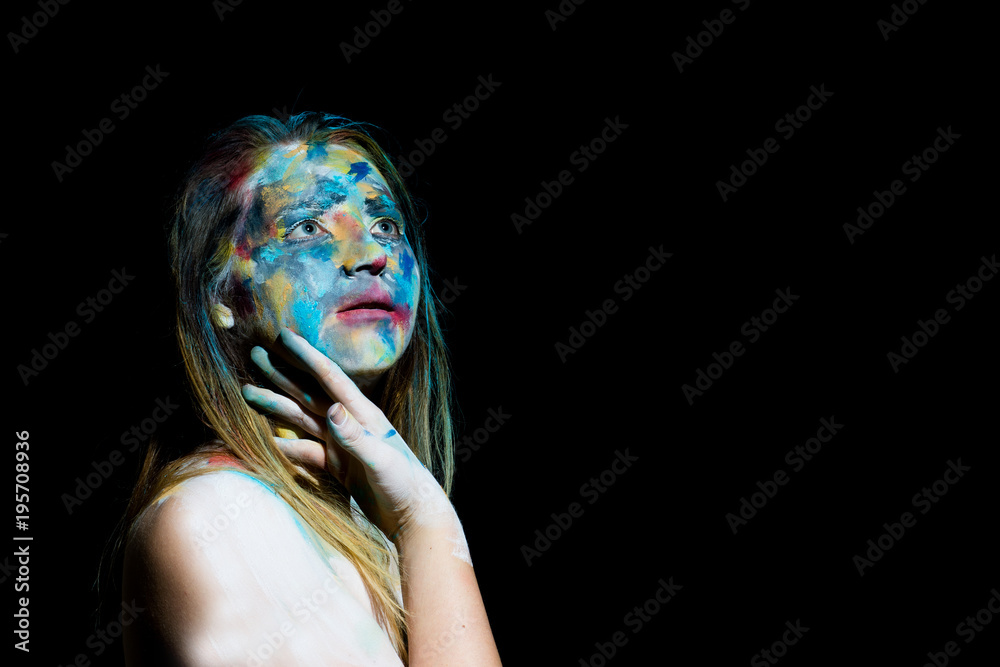 Naklejka premium A woman with abstract face paint looks at the camera