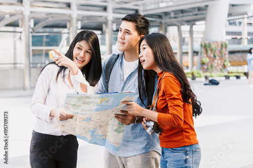 Group of young friends tourists standing and holding map in city.Traveler concept