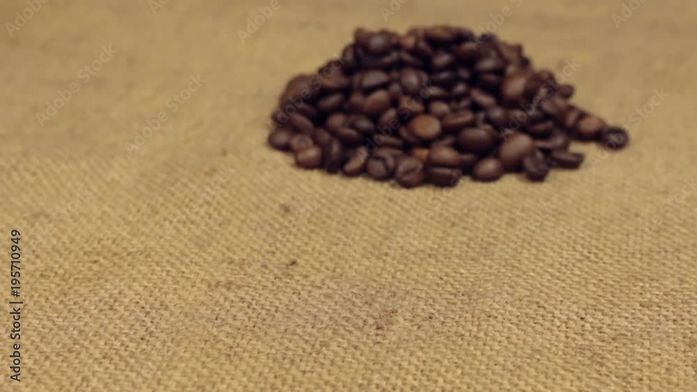 Zoom, approaching is a pile of coffee beans lying on burlap. Close-up Zoom, approaching is a pile of coffee beans lying on burlap. Close-up