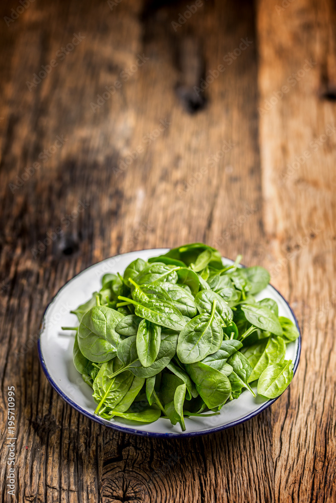 Spinach. Fresh baby spinach leaves in plate on woden table Spinach. Fresh baby spinach leaves in plate on woden table