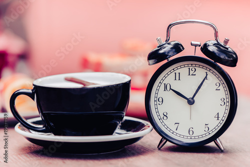 Black old clock with black coffee cup decoration on wooden table pink colortone