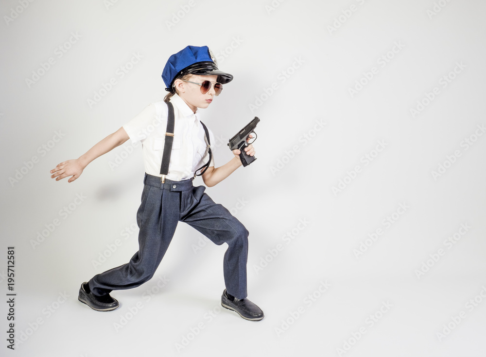 Little long-haired boy as a policeman runs, isolated on gray Little long-haired boy as a policeman runs, isolated on gray