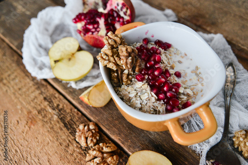 Breakfast: granola with pomegranate and walnuts and green Apple on natural wooden background rustic. The concept of healthy and high-carbon nutrition.