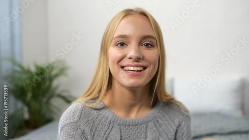 Thumb up. Cheerful nice woamn smiling and talking with her subscribers while sitting in the bedroom