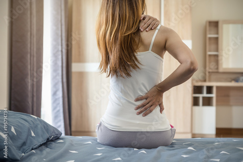 Woman suffering from back ache on the bed photo