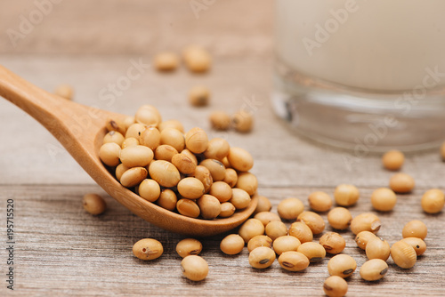 Soy beans in spoon on wooden background
