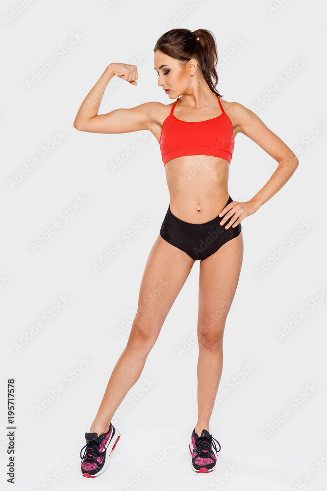 Young athletic woman with yellow dumbbells trains muscles of hands standing on a light background Young athletic woman with yellow dumbbells trains muscles of hands standing on a light background