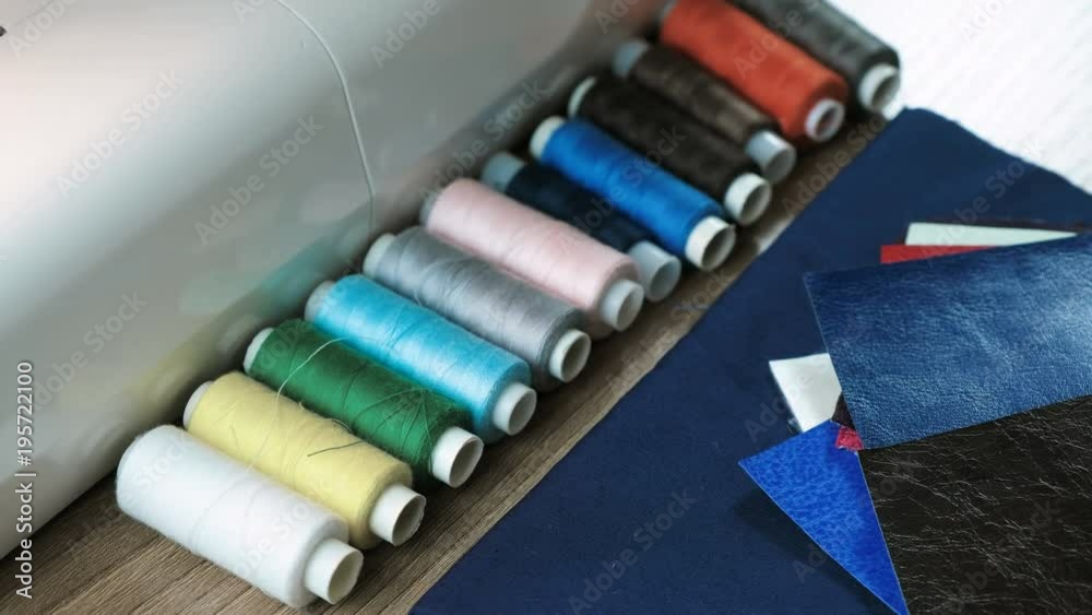 Multicolored coil threads, leather fabric lying on the table next to the sewing machine. Multicolored coil threads, leather fabric lying on the table next to the sewing machine.