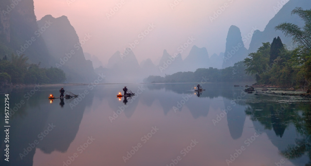 The Li River, Xingping, China, scenic landscape. Cormorant fishermans on the ancient bamboo boats with a lighted lamps at sunrise. - obrazy, fototapety, plakaty 