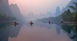 The Li River, Xingping, China, scenic landscape. Cormorant fishermans on the ancient bamboo boats with a lighted lamps at sunrise.