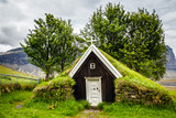 Icelandic traditional turf church covered with grass,  trees and rocks in the background near Kalfafell village, South Iceland