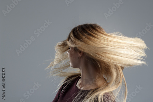 A girl with very well-groomed hair has fun at the camera and wags her head, a good mood, abstract photos of beautiful hair