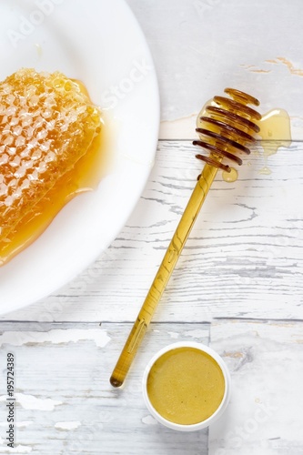 tasty organic honey in a honeycomb and honey lip balm on a wooden, vintage background