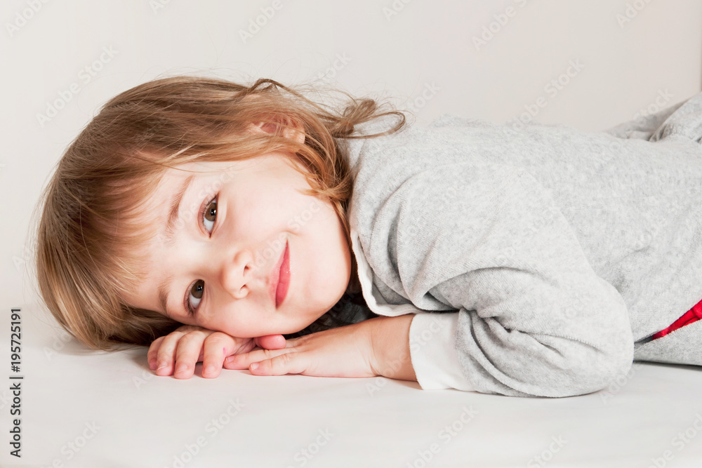 Portrait of little baby girl lies on light floor