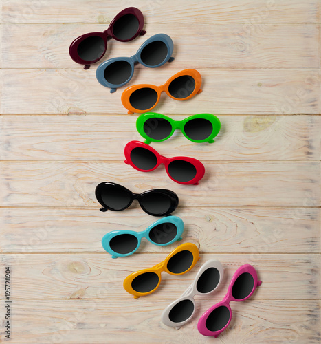 Collection of fashionable multi-colored sunglasses - a trend of summer on wooden background.