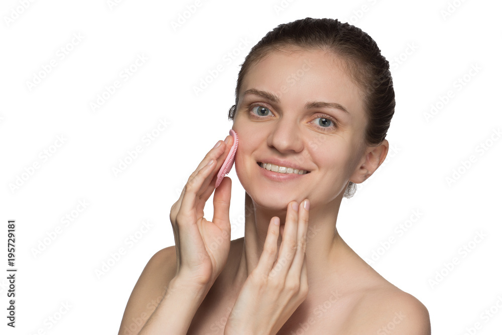Beautiful young female model smiling and peeling face and nose with silicone brush on white background Beautiful young female model smiling and peeling face and nose with silicone brush on white background