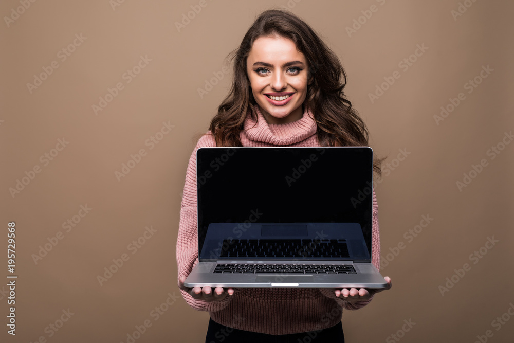 Naklejka premium Happys woman showing blank laptop computer screen on brown background