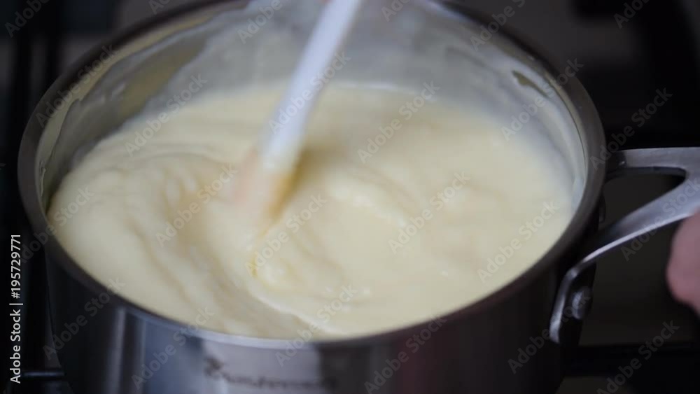 WOMAN MAKING CUSTARD IN SAUCEPAN ON COOKER HOB WOMAN MAKING CUSTARD IN SAUCEPAN ON COOKER HOB