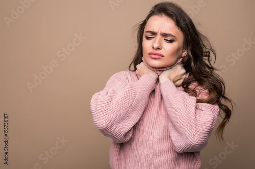 Young woman with sore throat isolated on brown background photo