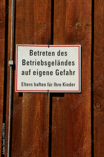 German Sign: "Enter the premises at your own risk", Schild vor einem Betriebsgelände