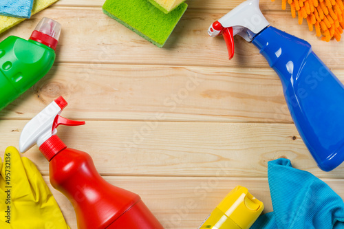 Cleaning concept - cleaning supplies on wood background