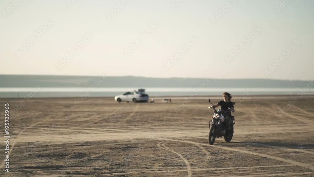 beautiful young woman riding on an old motorcycle and doing a trick. in the desert at sunset or sunrise. Female biker. Stabilized shot beautiful young woman riding on an old motorcycle and doing a trick. in the desert at sunset or sunrise. Female biker. Stabilized shot